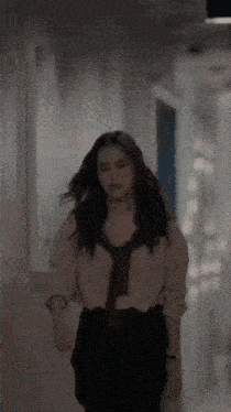 a woman is walking down a hallway wearing a tie and a shirt .