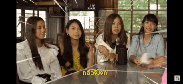 a group of young women are sitting at a table with a foreign language written on the screen