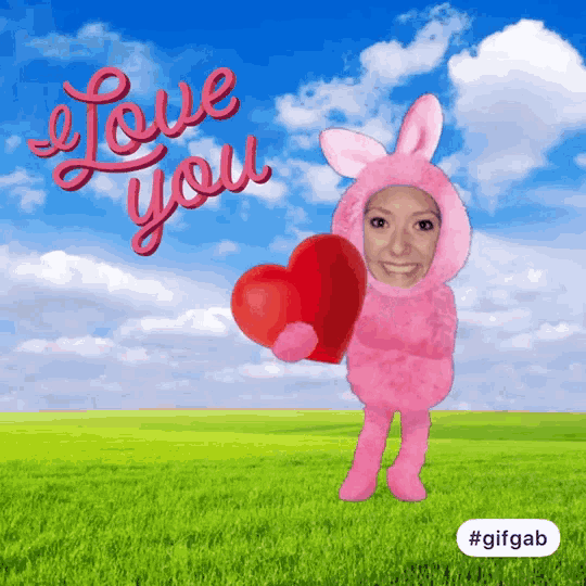 a woman in a pink bunny costume is holding a heart and says " i love you " behind her