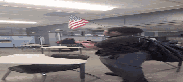 a man with a backpack stands in front of a flag