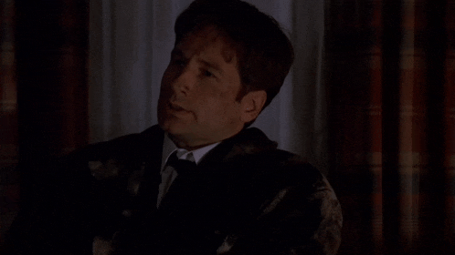 a man in a suit and tie is sitting in the dark