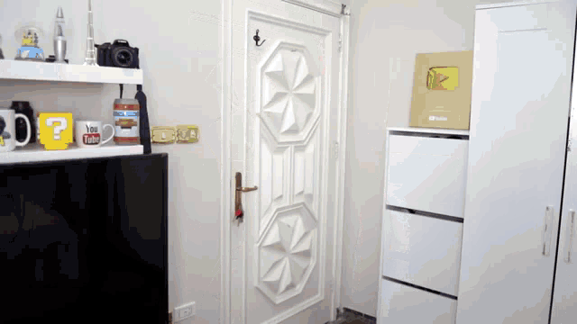 a room with a door and a shelf with a mug that says " you tube "