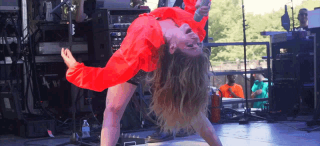 a woman in a red shirt is holding a microphone upside down on a stage