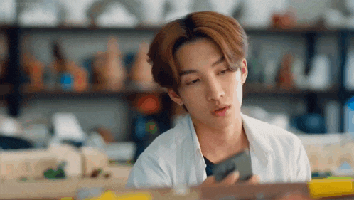 a young man is using a cell phone in a room .