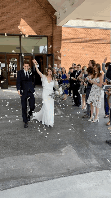 a bride and groom are walking through a confetti shower