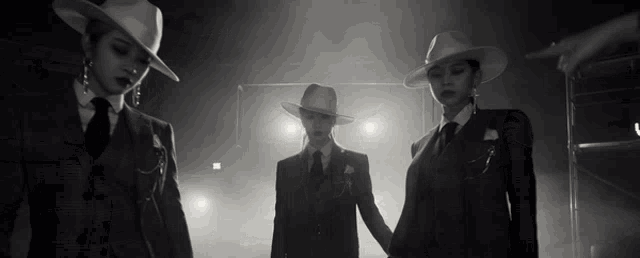 three women in suits and hats are standing next to each other in a dark room