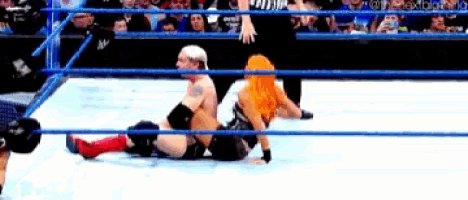 a man and a woman are wrestling in a wrestling ring while a referee watches .