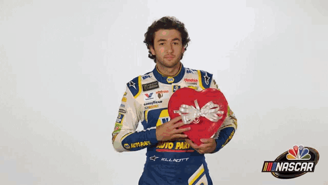 a nascar driver is holding a red heart in his hands