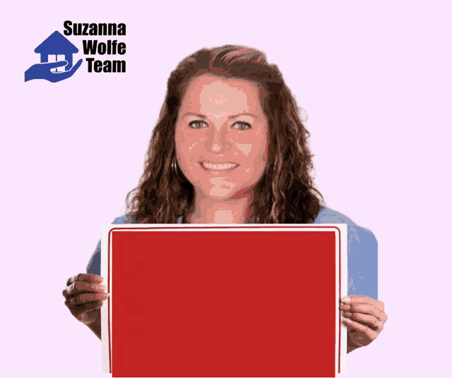 a woman holding a sold sign with a house on it