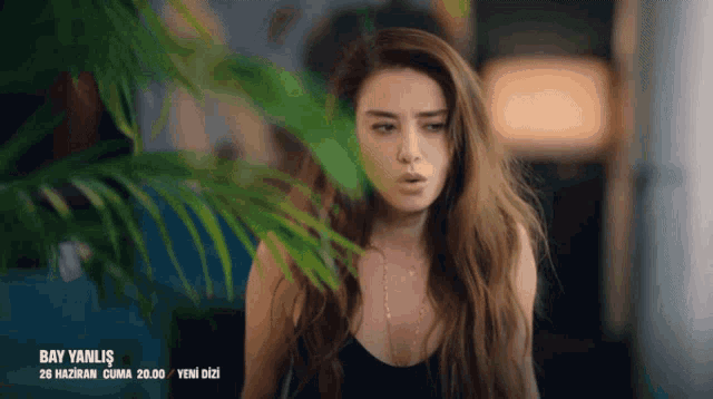 a woman in a black top is standing in front of a palm tree with the words bay yanlis 26 haziran cuma 20.00 yeni dizi below her