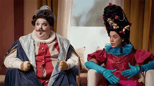 a man and a woman in costumes are sitting in chairs .