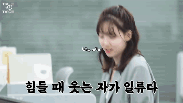 a woman sitting at a desk with korean writing on the screen