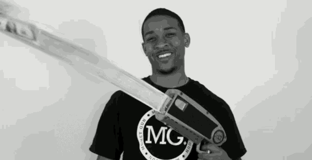 a man wearing a black shirt that says mg is holding a gun