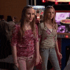 two girls standing in front of a jump jump arcade game