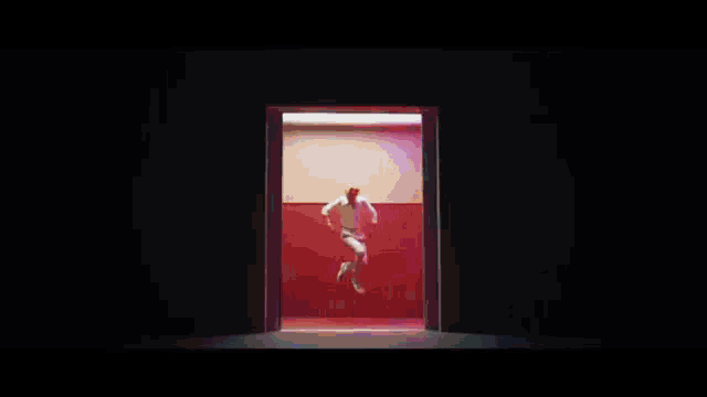 a man is dancing in front of a red wall in a room .