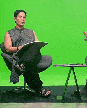 a woman sits in a chair with her legs crossed