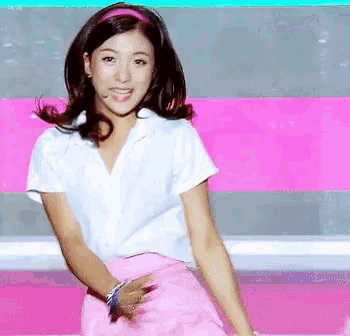 a woman in a white shirt and pink skirt smiles