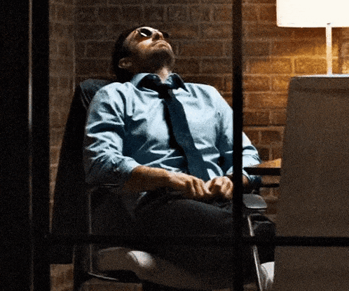 a man in a blue shirt and tie is sleeping in a chair