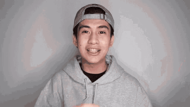 a young man wearing a hat and braces is pointing at the camera .