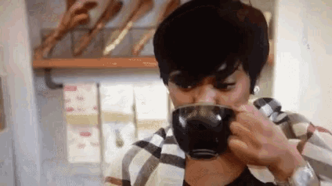 a woman is drinking a cup of coffee from a black cup .
