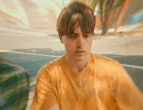 a young man wearing a yellow shirt is looking at something