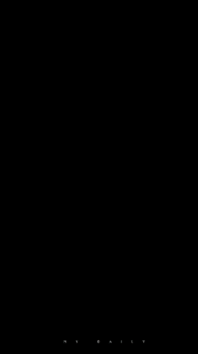 a woman with long hair and a necklace is standing in front of a black screen .