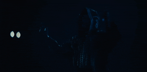 a man is singing into a microphone in a dark room