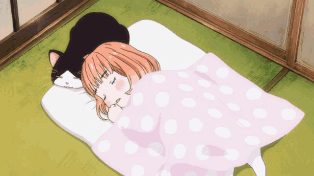 a girl and a cat are sleeping on a bed with a pink polka dot blanket
