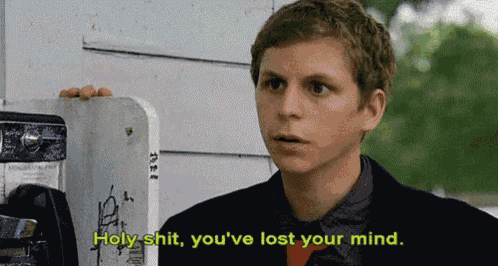 a man is standing in front of a payphone and says holy shit you 've lost your mind