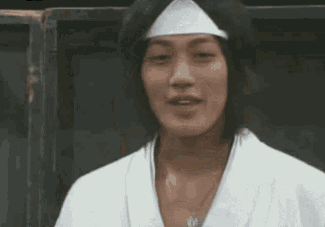 a man wearing a white robe and a bandana on his head is making a funny face .