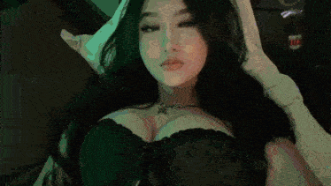 a woman is laying on a bed wearing a black bra and a purple necklace .
