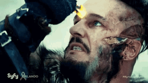 a man with a beard is holding a torch to his forehead .