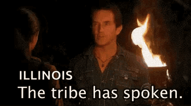 a woman is smiling while holding a torch in front of a fire and the words illinois the tribe has spoken .