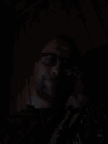 a man wearing glasses and a blue shirt looks down at the camera