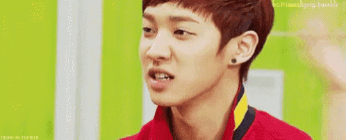 a young man in a red shirt is making a funny face and the word shit is on the screen .