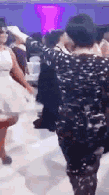 a woman in a white dress is dancing with a man in a black shirt at a party .