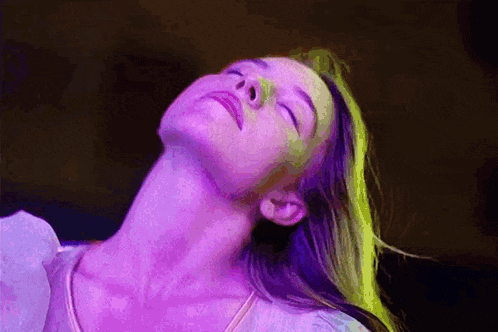 a woman with her eyes closed is surrounded by purple lights .