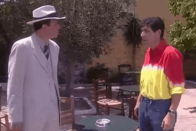 two men standing next to each other in front of a table