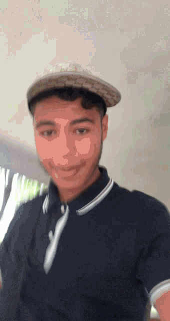 a young man wearing a hat and a polo shirt is smiling