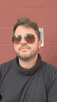 a man wearing sunglasses and a black shirt looks down