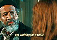 a man with a beard is talking to a woman who is waiting for a table
