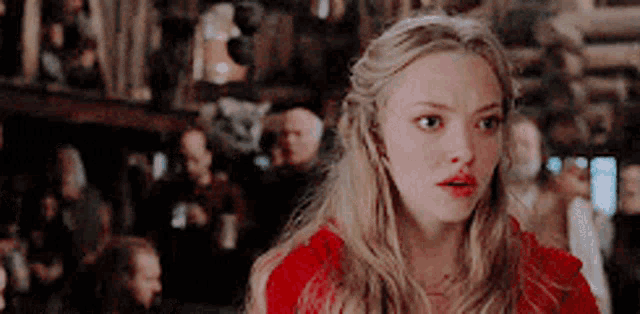 a woman in a red dress is standing in front of a group of people .