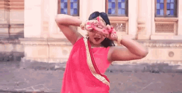 a woman in a pink dress is dancing in front of a building .