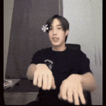 a young man is sitting at a desk with his hands outstretched and making a funny face .