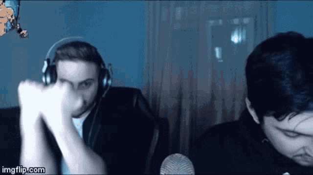a man wearing headphones holds his fist up in front of a microphone