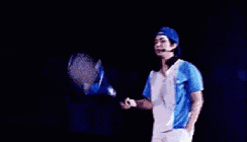 a man in a blue and white shirt is holding a tennis racquet on a stage .