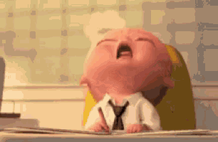 a baby is crying while sitting at a desk with a pencil in his hand .