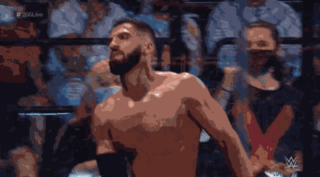 a shirtless wrestler stands in front of a crowd with the hashtag # 205live in the corner