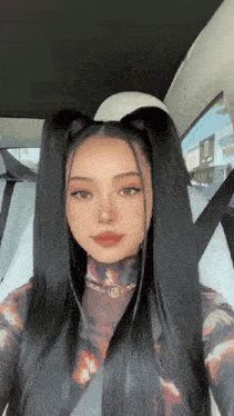 a woman with long black hair is sitting in a car with a seat belt on .