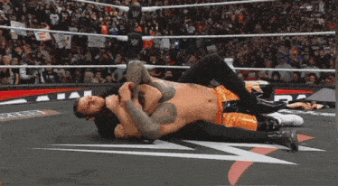a wrestling match is going on in front of a crowd with a sign that says " feed the up "